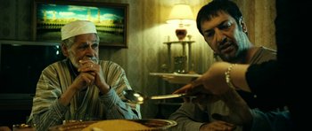 Movie still from “22 Bullets” (2010), directed by Richard Berry – Two men sitting at a dinner table with spoons; Medium shot, Over the shoulder angle