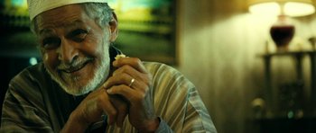 Movie still from “22 Bullets” (2010), directed by Richard Berry – An older man with a beard and a ring around his neck; Close Up shot, Low angle