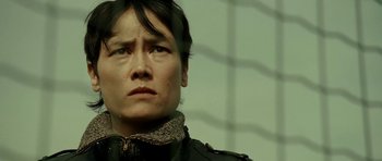 Movie still from “22 Bullets” (2010), directed by Richard Berry – A woman with a black jacket looking at the camera; Close Up shot, Low angle