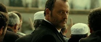 Movie still from “22 Bullets” (2010), directed by Richard Berry – A person wearing a suit and tie; Close Up shot, Low angle