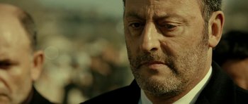 Movie still from “22 Bullets” (2010), directed by Richard Berry – An older man in a suit and tie looking to his left; Close Up shot, Low angle