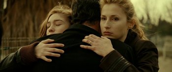 Movie still from “22 Bullets” (2010), directed by Richard Berry – A man and two women hugging each other; Close Up shot, Over the shoulder angle