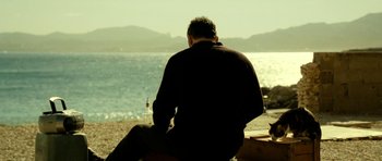 Movie still from “22 Bullets” (2010), directed by Richard Berry – A man sitting on the beach looking out at the water; Medium shot, Over the shoulder angle