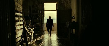 Movie still from “22 Bullets” (2010), directed by Richard Berry – A man in a suit walking through a door way; Wide shot, Low angle