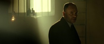 Movie still from “22 Bullets” (2010), directed by Richard Berry – A man standing in a dimly lit room; Close Up shot, Low angle