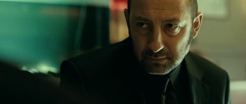 Movie still from “22 Bullets” (2010), directed by Richard Berry – A person wearing a suit and tie; Close Up shot, Over the shoulder angle