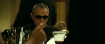 Movie still from “22 Bullets” (2010), directed by Richard Berry – A man sitting at a table with a glass of red wine; Close Up shot, Over the shoulder angle