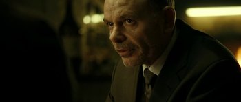 Movie still from “22 Bullets” (2010), directed by Richard Berry – A person wearing a suit and tie; Close Up shot, Over the shoulder angle