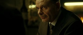 Movie still from “22 Bullets” (2010), directed by Richard Berry – A person wearing a suit and tie; Close Up shot, Over the shoulder angle