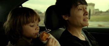 Movie still from “22 Bullets” (2010), directed by Richard Berry – A man and a child in the back seat of a car; Close Up shot, Over the shoulder angle