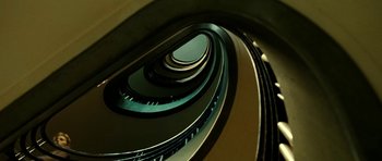Movie still from “22 Bullets” (2010), directed by Richard Berry – Looking down at a spiral staircase in a building; Extreme Wide shot, Overhead angle