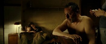 Movie still from “22 Bullets” (2010), directed by Richard Berry – A shirtless man sitting next to a woman in a bed; Medium shot, Over the shoulder angle