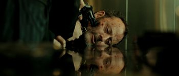 Movie still from “22 Bullets” (2010), directed by Richard Berry – A man holding a gun while laying on the ground; Close Up shot, Overhead angle