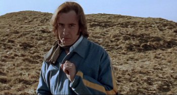 Movie still from “24 Hour Party People” (2002), directed by Tom Bruggen – A man standing in a field wearing a jacket and a tie; Close Up shot, Low angle