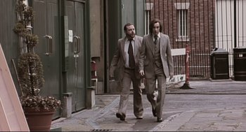 Movie still from “24 Hour Party People” (2002), directed by Tom Bruggen – A couple of men walking down a street; Wide shot, Low angle