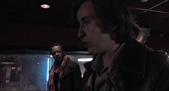 Movie still from “24 Hour Party People” (2002), directed by Tom Bruggen – Two men are standing next to each other in a dark room; Close Up shot, Low angle