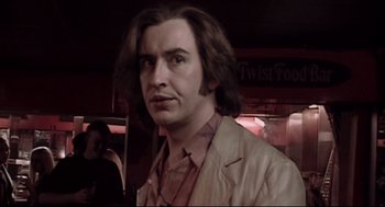 Movie still from “24 Hour Party People” (2002), directed by Tom Bruggen – A man with long brown hair standing in front of a crowd; Close Up shot, Low angle