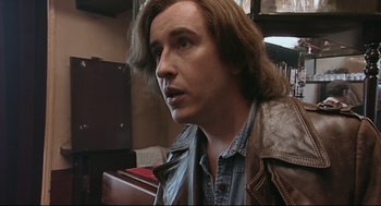 Movie still from “24 Hour Party People” (2002), directed by Tom Bruggen – A person with long hair; Close Up shot, High angle