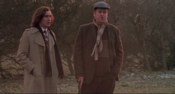 Movie still from “24 Hour Party People” (2002), directed by Tom Bruggen – A man and a woman standing next to each other in a field; Medium shot, Low angle