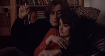 Movie still from “24 Hour Party People” (2002), directed by Tom Bruggen – A man and a woman sitting next to each other in a room; Medium shot, High angle