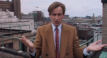 Movie still from “24 Hour Party People” (2002), directed by Tom Bruggen – A man wearing a suit and tie standing on top of a building; Close Up shot, High angle
