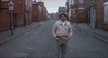 Movie still from “24 Hour Party People” (2002), directed by Tom Bruggen – A man standing on the side of a street; Wide shot, Low angle