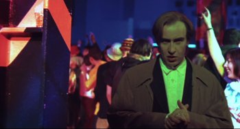 Movie still from “24 Hour Party People” (2002), directed by Tom Bruggen – A crowd of people standing in a room at night; Medium shot, Low angle