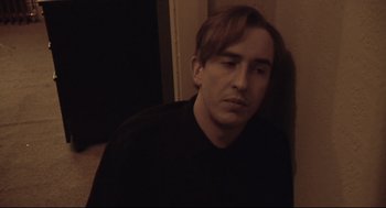 Movie still from “24 Hour Party People” (2002), directed by Tom Bruggen – A man sitting in front of a wall with his eyes closed; Close Up shot, High angle