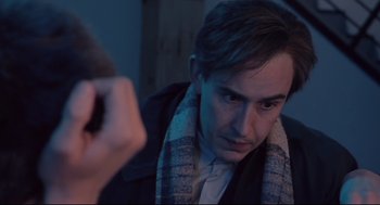 Movie still from “24 Hour Party People” (2002), directed by Tom Bruggen – A man with a scarf around his neck looking at his reflection in a mirror; Close Up shot, Over the shoulder angle