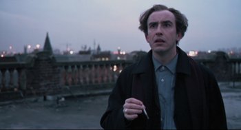 Movie still from “24 Hour Party People” (2002), directed by Tom Bruggen – A man holding a cigarette standing on a roof top; Close Up shot, Low angle