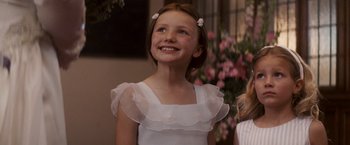 Movie still from “27 Dresses” (2008), directed by Anne Fletcher – A young girl in a white dress smiling for the camera; Close Up shot, Low angle