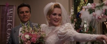 Movie still from “27 Dresses” (2008), directed by Anne Fletcher – A woman wearing a wedding dress and holding a bouquet of flowers; Medium shot, Over the shoulder angle