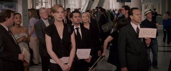 Movie still from “27 Dresses” (2008), directed by Anne Fletcher – A group of people standing in a crowd holding signs; Medium shot, Over the shoulder angle