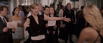 Movie still from “27 Dresses” (2008), directed by Anne Fletcher – A group of people standing in a crowd holding signs; Wide shot, Over the shoulder angle