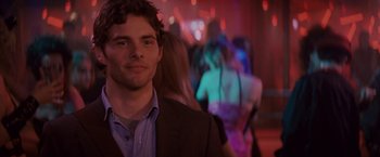 Movie still from “27 Dresses” (2008), directed by Anne Fletcher – A man in a suit standing in front of a group of people; Close Up shot, Over the shoulder angle