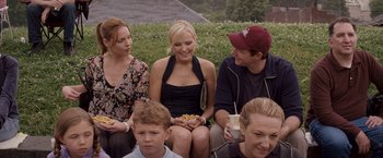 Movie still from “27 Dresses” (2008), directed by Anne Fletcher – A group of people sitting on the grass eating food; Medium shot, Over the shoulder angle