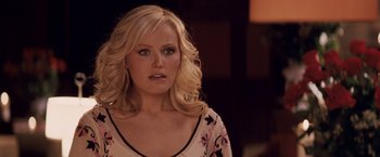 Movie still from “27 Dresses” (2008), directed by Anne Fletcher – A woman with blonde curly hair wearing a pink and black floral shirt; Close Up shot, Over the shoulder angle