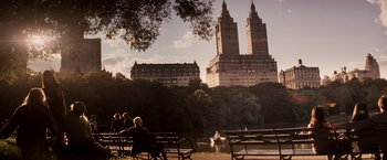 Movie still from “27 Dresses” (2008), directed by Anne Fletcher – People are sitting on park benches in front of a lake; Extreme Wide shot, Over the shoulder angle