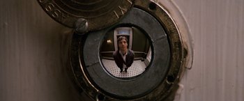 Movie still from “27 Dresses” (2008), directed by Anne Fletcher – A man standing inside of an elevator looking into a mirror; Extreme Close Up shot, Overhead angle
