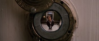Movie still from “27 Dresses” (2008), directed by Anne Fletcher – A man standing inside of an elevator looking into the camera; Extreme Close Up shot, Overhead angle