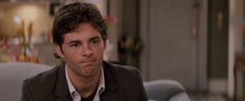Movie still from “27 Dresses” (2008), directed by Anne Fletcher – A man in a suit sitting in a room; Close Up shot, Over the shoulder angle