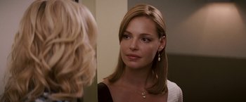 Movie still from “27 Dresses” (2008), directed by Anne Fletcher – A woman looking into a mirror while wearing a necklace; Close Up shot, Over the shoulder angle