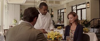 Movie still from “27 Dresses” (2008), directed by Anne Fletcher – A man in a chef's outfit serving a plate of food to two women; Medium shot, Over the shoulder angle