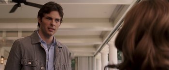 Movie still from “27 Dresses” (2008), directed by Anne Fletcher – A man standing next to a woman in a hallway; Close Up shot, Over the shoulder angle