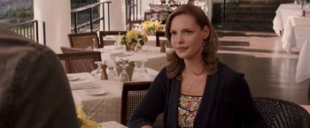 Movie still from “27 Dresses” (2008), directed by Anne Fletcher – A woman sitting at a table in front of a bunch of flowers; Medium shot, Over the shoulder angle