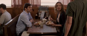 Movie still from “27 Dresses” (2008), directed by Anne Fletcher – A man and a woman sitting at a table with plates of food; Medium shot, Over the shoulder angle