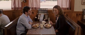Movie still from “27 Dresses” (2008), directed by Anne Fletcher – A man and a woman sitting at a table with plates of food; Medium shot, Over the shoulder angle