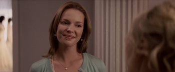 Movie still from “27 Dresses” (2008), directed by Anne Fletcher – A person smiling for a picture; Close Up shot, Over the shoulder angle