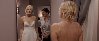 Movie still from “27 Dresses” (2008), directed by Anne Fletcher – A woman looking in the mirror while standing in front of a mirror; Medium shot, Over the shoulder angle