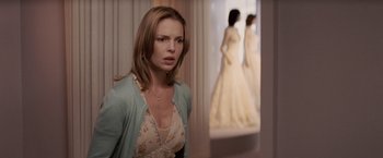 Movie still from “27 Dresses” (2008), directed by Anne Fletcher – A woman standing in front of a window looking at the camera; Medium shot, Over the shoulder angle